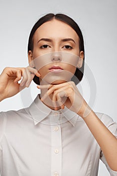 Portrait of a beautiful pacified woman in a white shirt on a light background