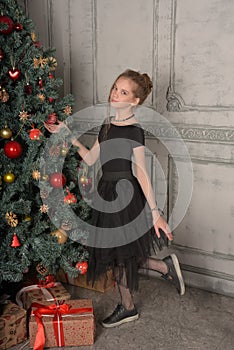 Portrait of a beautiful pensive girl in black near the Christmas tree at Christmas