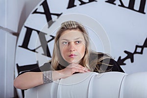 Portrait of beautiful pensive woman with big clock on background