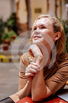 Portrait of beautiful pensive woman grins, grinning, eyes glistening, young Caucasian female person at cafe, smiling blonde girl