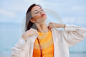 Portrait of a beautiful pensive woman with tanned skin in a white beach shirt with wet hair after swimming on the beach