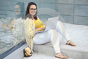 Portrait of beautiful plus size woman 30-35 years old in fashion clothes and eyeglasses working remotely on a laptop