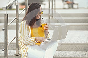 Portrait of beautiful plus size woman 30-35 years old in fashion clothes and sunglasses working remotely on a laptop