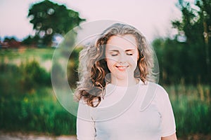 Portrait Of Beautiful Plus Size Young Woman In White Shirt Posing In Summer Field Meadow At Sunset Background