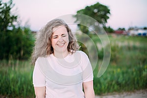 Portrait Of Beautiful Plus Size Young Woman In White Shirt Posing In Summer Field Meadow At Sunset Background