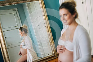 Portrait of a beautiful pregnant woman in front of a mirror at home