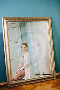 Portrait of a beautiful pregnant woman in front of a mirror at home