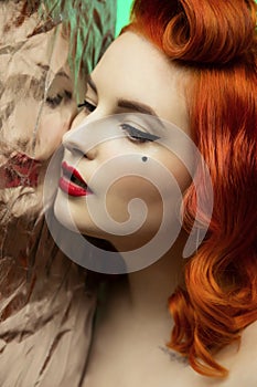 Portrait of a beautiful red-hair girl with pin up make up and hair
