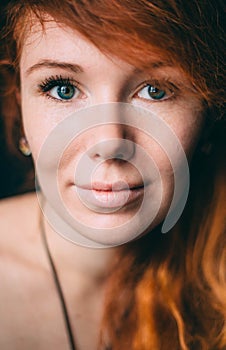 Vertical portrait of a beautiful red-haired curly girl with make-up and jewelry