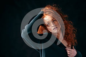 Portrait of a beautiful red-haired curly-haired girl on a black background