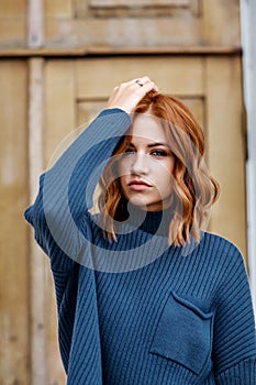 Portrait of a beautiful red-haired girl in a blue sweater