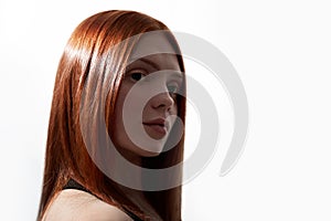 Portrait of a beautiful red-haired girl with straight hair. The girl looks to the side on a white isolated background