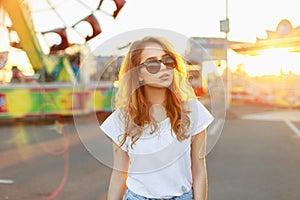 Portrait of a beautiful red-haired girl in sunglasses at sunset