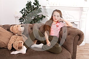 Portrait of a beautiful redhead teen girl. Cute girl sitting on the sofa, smiling and looking at the camera
