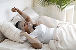 Portrait of beautiful relaxed african american woman stretching hands after waking up