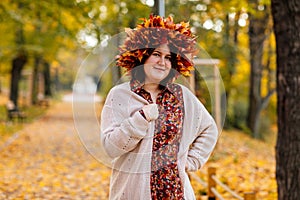 Portrait of beautiful romantic young woman with wreath of autumn yellow brown golden and red maple leaves, cute stylish girl in