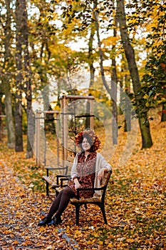 Portrait of beautiful romantic young woman with wreath of autumn yellow brown golden and red maple leaves, cute stylish girl