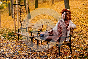 Portrait of beautiful romantic young woman with wreath of autumn yellow brown golden and red maple leaves, cute stylish girl