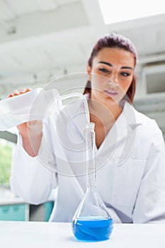 Portrait of a beautiful scientist pouring liquid