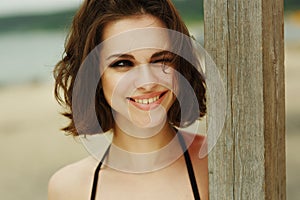 Portrait of a beautiful and seductive young woman in a black bikini with loose brown hair and sexy makeup