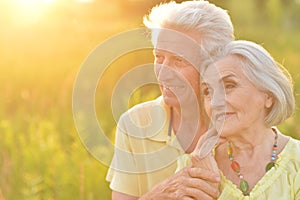 Portrait of beautiful senior couple hugging on a lilac background in the park