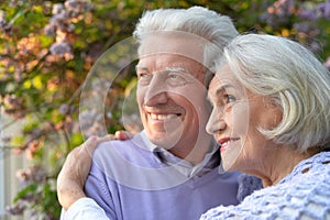 Portrait of beautiful senior couple hugging in the park by lilacs