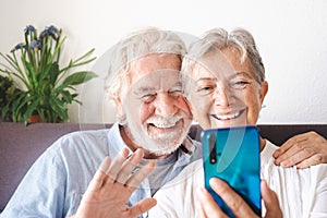 Portrait of beautiful senior couple sitting at home smiling using mobile phone