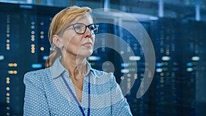 Portrait of a Beautiful Senior Female IT Technician Standing In Modern Data Center. In the Backgro