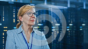 Portrait of a Beautiful Senior Female IT Technician Standing In Modern Data Center. In the Backgro