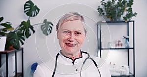Portrait of beautiful senior grey haired Caucasian doctor woman wear white medical coat, stethoscope smiling at camera.