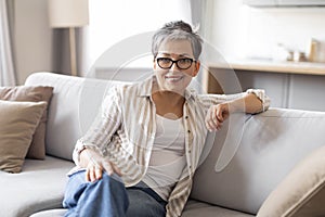 Portrait of beautiful senior woman relaxing on comfortable couch at home