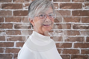 Portrait of beautiful senior woman with white hair - brick wall in background