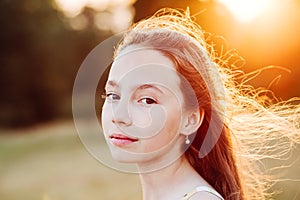 Portrait of Beautiful serious Teen Girl is enjoying nature in the park at Summer sunset