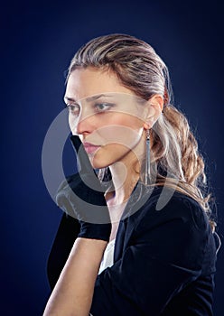 Portrait of beautiful serious woman in black gloves holding finger near lips