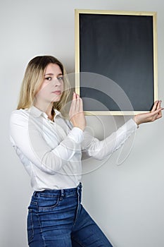 Portrait of a beautiful serious young blonde woman holding a blank whiteboard at face height