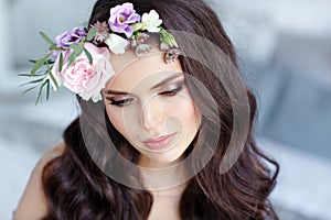 Portrait of a beautiful brunette girl with brown eyes in a delicate dress and a wreath of flowers on her head