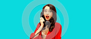 Portrait of beautiful sexy brunette woman talking on retro phone isolated on blue background, pin up style
