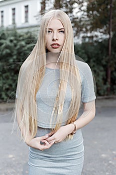 Portrait of a beautiful cute girl with long blond hair in a gray suit with full lips