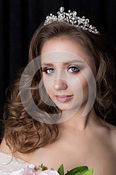 Portrait of a beautiful cute young girl bride with a beautiful wedding ceremony evening hair and makeup with a crown on the h