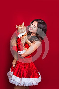 Portrait of beautiful girl wearing santa claus clothes with red british cat