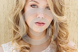 Portrait of a beautiful smiling happy girl with big full lips with blond hair in a white dress on a sunny bright day