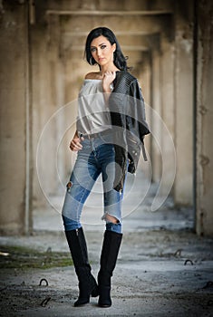 Portrait of beautiful young woman with modern outfit, leather jacket, jeans, white blouse and black boots