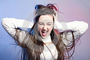 Portrait of a beautiful shocked girl with long hair on studio background, a young woman opened her mouth , grabbed head with hands