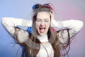 Portrait of a beautiful shocked girl with long hair on studio background, a young woman opened her mouth , grabbed head with hands