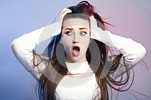 Portrait of a beautiful shocked girl with long hair on studio background, a young woman opened her mouth in surprise, concept