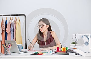 Portrait of beautiful smile asian designer woman with computer in tailer fabric fashion small business workshop.