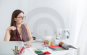 Portrait of beautiful smile asian designer woman with computer in tailer fabric fashion small business workshop.