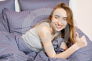 Portrait of a beautiful smile girl on the bed after sleep, woman show like sign in bed