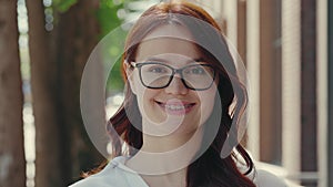 Portrait of the beautiful smiled ginger business woman wearing formal suit standing near the business centre looking at