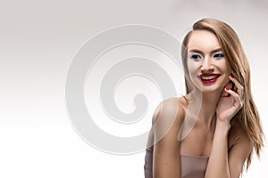 Portrait of the beautiful smiling blonde girl with red lips and